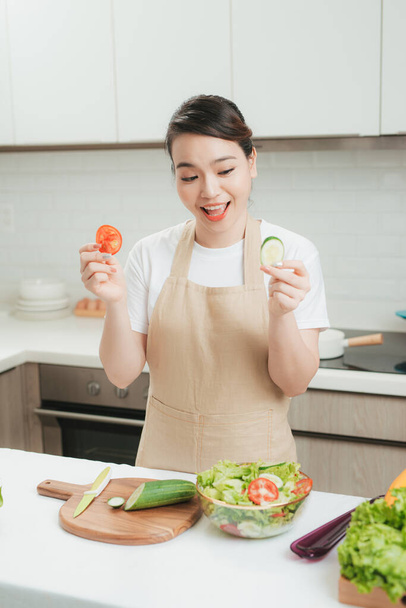Mujer saludable hace ensalada de verduras frescas con aceite de oliva, tomate y ensalada - Foto, Imagen