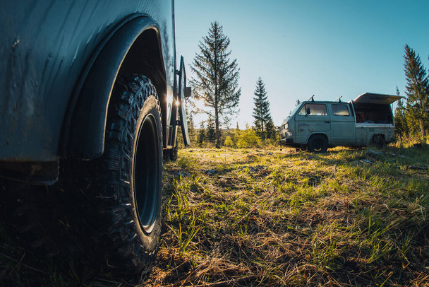 Dois velhos vintage costume offroad campervans estacionados nas horas da manhã na planície da floresta. Vista do grave pneu off road pisar em um carro. - Foto, Imagem