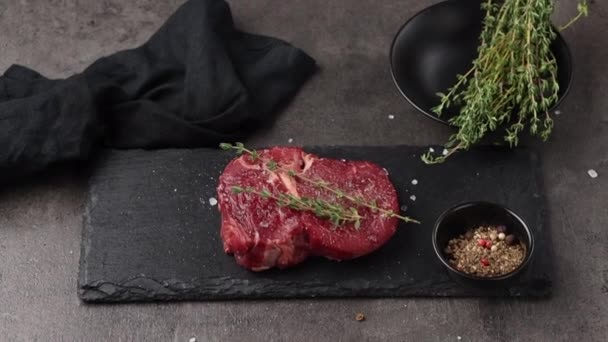 tranche de viande de bœuf cru frais sur plaque de pierre noire zoom avant. viande et épices sur la table de cuisine vue du dessus - Séquence, vidéo