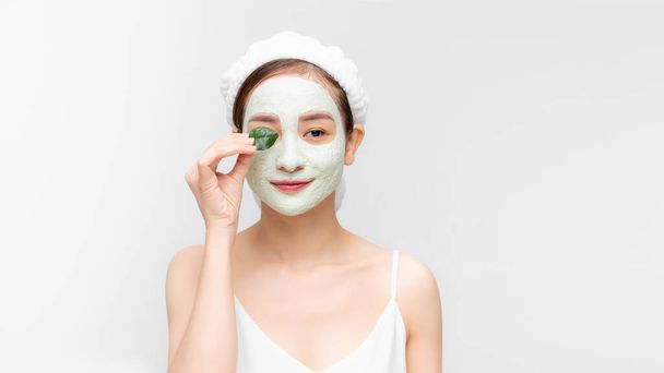 Young beautiful woman in face mask of therapeutic blue mud. Spa treatment, self care and healthy skin. Copy space, white background - Photo, image