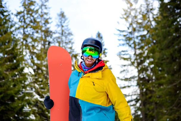 Portrait of Young Snowboarder with the Snowboard in the Winter Forest. Snowboarding and Winter Sports Concept - Фото, изображение