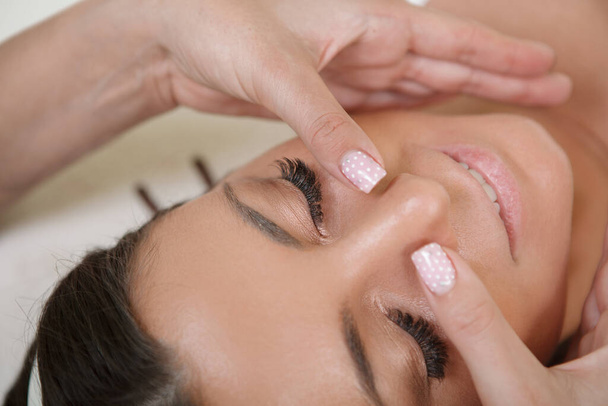 Cropped close up of a woman enjoying anti-aging face massage - Photo, image