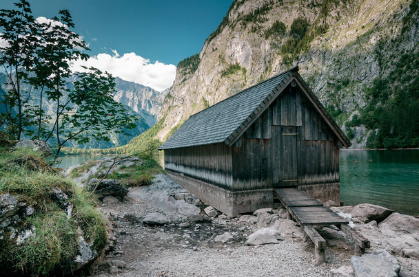 A small wooden cabin on a lake surrounded by cliffs - Foto, Imagem