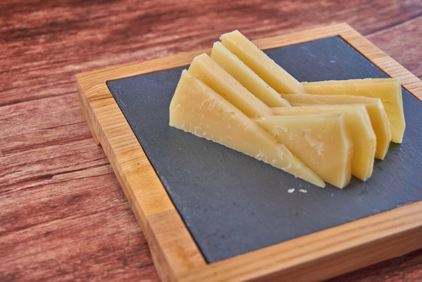 A tray of cheese on a wooden table - Photo, Image