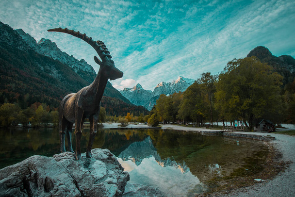 Capricornio estatua en el lago Jasna en kranjska gora a principios de otoño. - Foto, Imagen