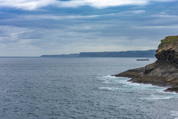 A beautiful scenery of the sea with the rocks under the cloudy sky in Santander Spain - Foto, Imagen
