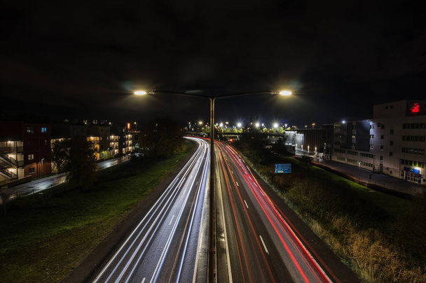 Night timelapse or nightlapse of a motorway in stockholm during cloudy night. Car trails are seen on the road. - Фото, зображення