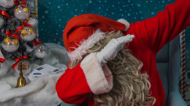 Санта-Клаус робить жест рук. Забавна Санта робить знак мазків на святковому фоні з ялинкою видимою
. - Фото, зображення