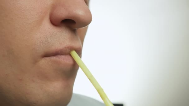 Lippen van een jonge man drinken door een cocktail tube, close-up, lichte achtergrond - Video