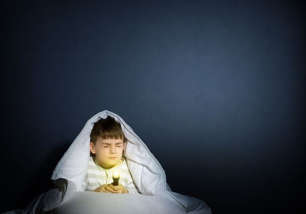boy under the covers with a flashlight - Foto, Imagen