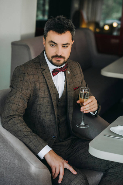 Portrait of handsome man in business suit holds glass . a glass of champagne in the hand of a brutal man - Fotografie, Obrázek