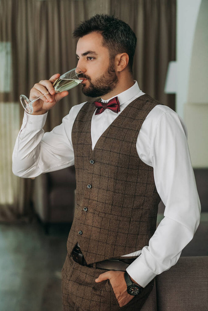 Portrait of handsome man in business suit holds glass . a glass of champagne in the hand of a brutal businessman - Foto, immagini