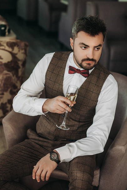 Portrait of handsome man in business suit holds glass . a glass of champagne in the hand of a brutal businessman - Valokuva, kuva