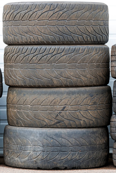 Uma pilha de pneus velhos e usados. os pneus estão sujos e desgastados, restando muito pouco piso. O texto REPLACE TIRE é visível nos pneus. - Foto, Imagem