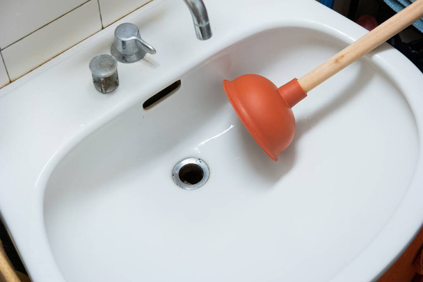 Wooden handle plunger with suction cup next to bathroom sink drain no people. - Photo, Image