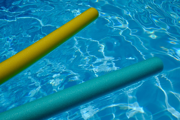 yellow and blue noodles in swimming-pool. blue water. - Photo, Image