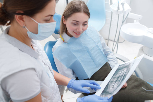 Female patient talking to her dentist, looking at dental x-ray scan - Foto, Imagen