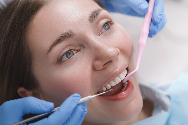 Close up of a woman with healthy white teeth getting dental examination by professional dentist - Foto, immagini