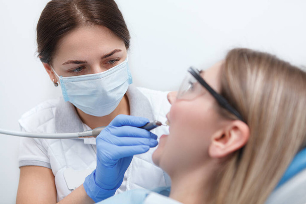 Close up of a professional dentist wearing medical face mask, examining teeth of patient - Foto, imagen