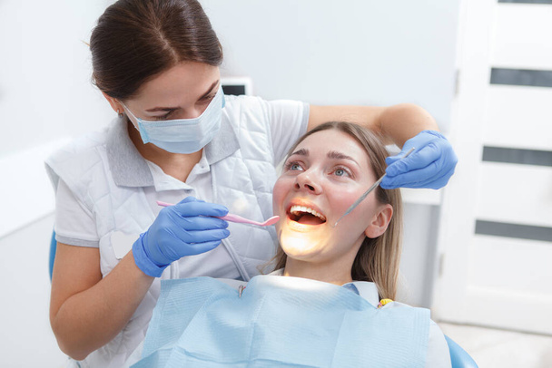 Young woman getting her teeth checked by dentist - Foto, imagen