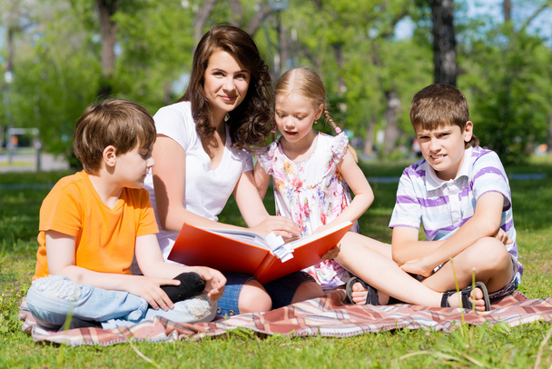 teacher reads a book to children in a summer park - Foto, Imagem