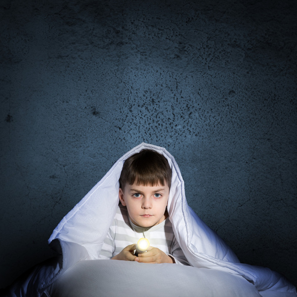 boy under the covers with a flashlight - Φωτογραφία, εικόνα