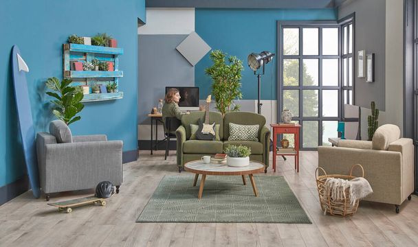 Tini lány eltölteni egy kis időt a szobában, dekoratív nappali kék fal munkaasztal háttér, bútorok zöld kanapé szürke fotel könyvespolc szőnyeg és középső asztal stílus. - Fotó, kép