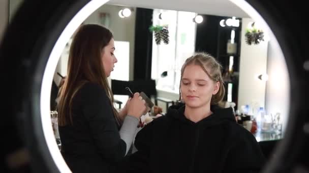 Vrouw make-up voor aantrekkelijke blonde haar vrouw in de studio. Video van make-up kunstenaar toepassen van cosmetica voor mooi model. Digitale camera maken video voor vlog - Video