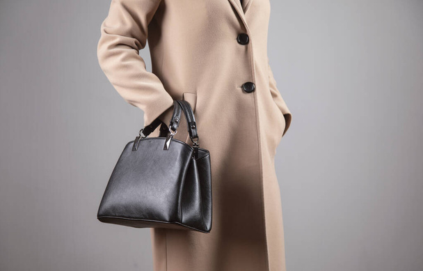 elegant woman in coat holding black bag - Fotoğraf, Görsel
