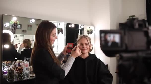 Woman making a video for her blog of making makeup, digital camera on tripod. Young female blogger on camera screen while doing makeup - Footage, Video
