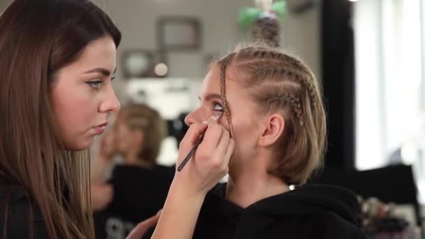 Γυναίκα κάνει μακιγιάζ για ελκυστική ξανθιά γυναίκα μαλλιά στο στούντιο. Βίντεο του καλλιτέχνη μακιγιάζ εφαρμογή καλλυντικών για όμορφο μοντέλο - Πλάνα, βίντεο