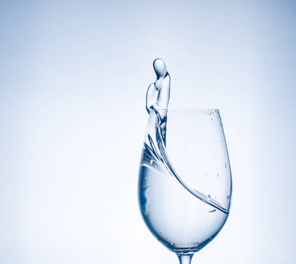water in een glas in de vorm van een glazen plons water mooie plons helder water rust en zuiverheid - Foto, afbeelding