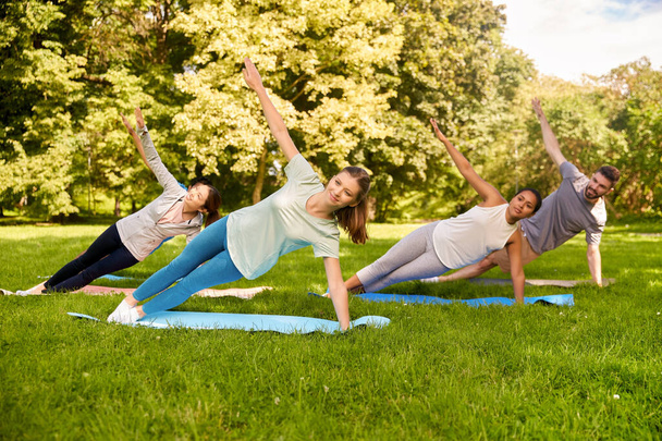 group of people doing yoga at summer park - Zdjęcie, obraz