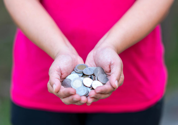 Konzept des Sparens durch die Verwendung von Münzen in den Händen der Menschen. - Foto, Bild