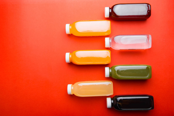 Photo of many detox juice bottles over red background with copyspace - Photo, Image
