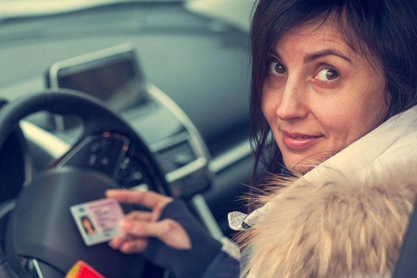 Získání řidičského průkazu, ženské ruce ukazují US řidičský průkaz, uprostřed volantu auta, tónovaný - Fotografie, Obrázek