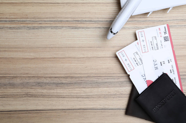 Avia tickets, passports and plane on wooden table, flat lay with space for text. Travel agency concept - Foto, afbeelding