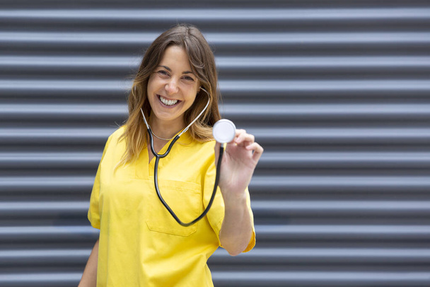 Portret uśmiechniętej młodej pielęgniarki w mundurze za pomocą stetoskopu. Miejsce na tekst. - Zdjęcie, obraz