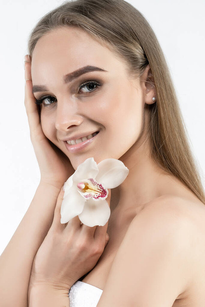 Smiling attractive girl with clean skin, charmingly smiles and touches her face with her hands. Cosmetology, health and beauty. - Fotografie, Obrázek