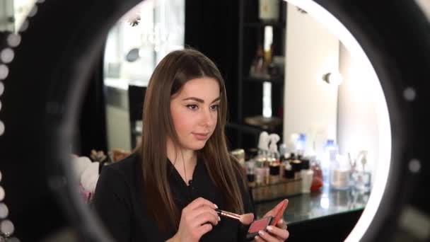 Young beautiful woman and professional beauty make up artist blogger recording makeup tutorial in beuty studio to share on website or social media. Woman use ring lamp and digital camera - Footage, Video