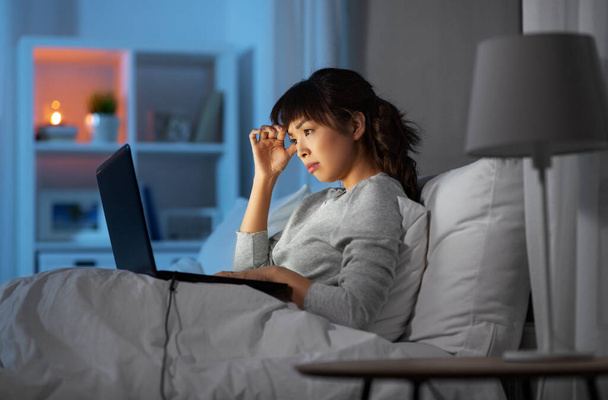 stressed woman with laptop working in bed at night - Fotoğraf, Görsel