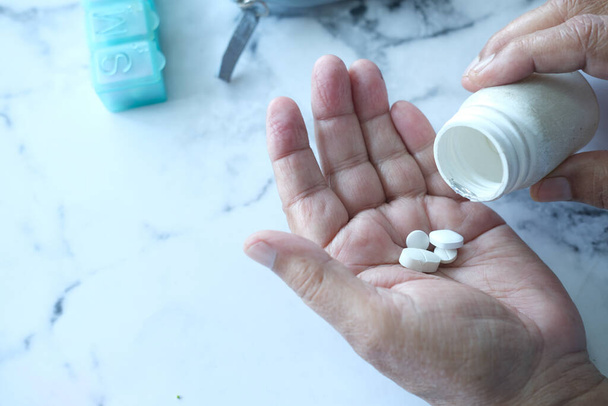 mão de homem sênior com medicamento derramado para fora do recipiente da pílula  - Foto, Imagem