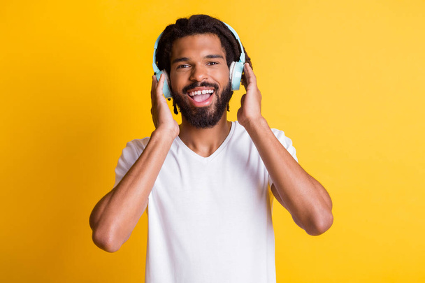 Photo of young black guy hold earphones open mouth toothy smile wear headphones white t-shirt isolated yellow color background - Fotoğraf, Görsel