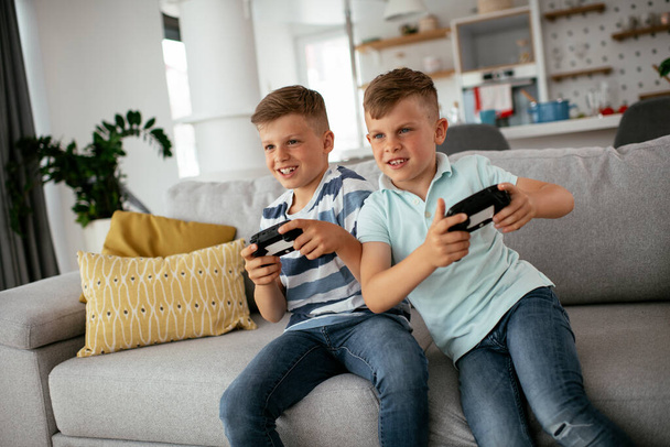 Glückliche Brüder, die Videospiele spielen. Junge Brüder haben Spaß beim Spielen von Videospielen im Wohnzimmer - Foto, Bild