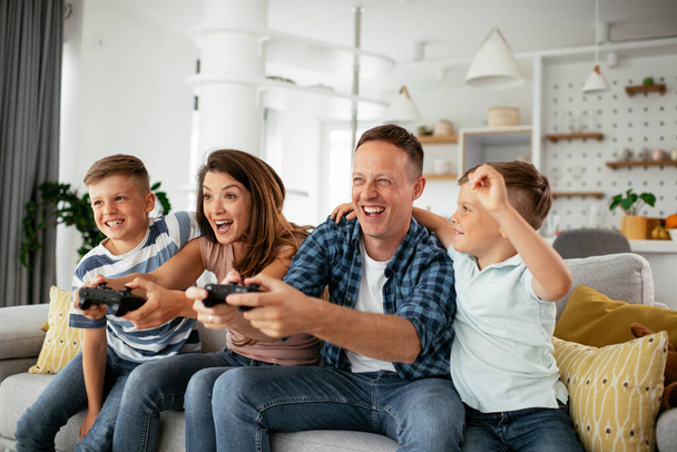  Onnellinen rakastava pari pelaa videopelejä lasten kanssa kotona. - Valokuva, kuva