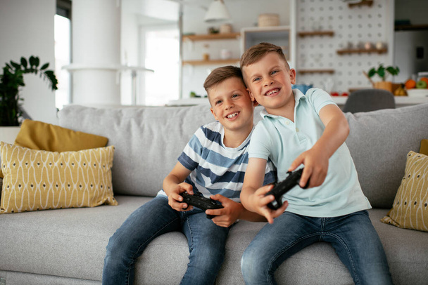 Szczęśliwi bracia grający w gry wideo. Młodzi bracia bawią się podczas gry wideo w salonie - Zdjęcie, obraz