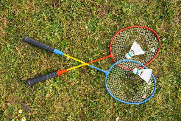 Raquettes de badminton et des navettes de différentes couleurs sont sur la pelouse verte - Photo, image