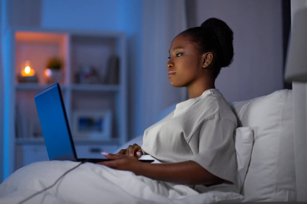 woman with laptop in bed at home at night - Photo, image