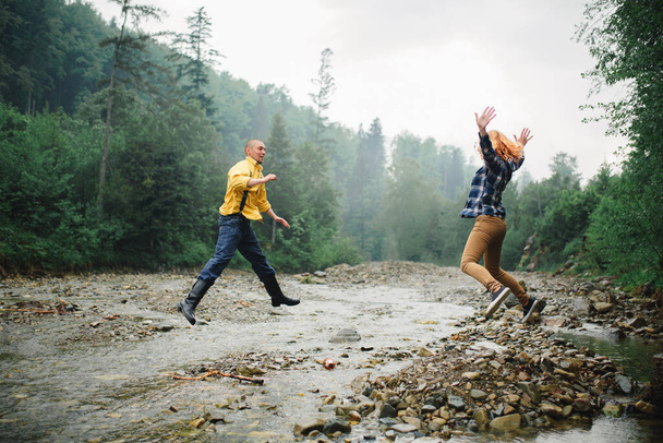 Playful happy handsome couple having while walking in woods. tourists in the mountains. Adventure in nature concept. couple in the mountains - Photo, Image