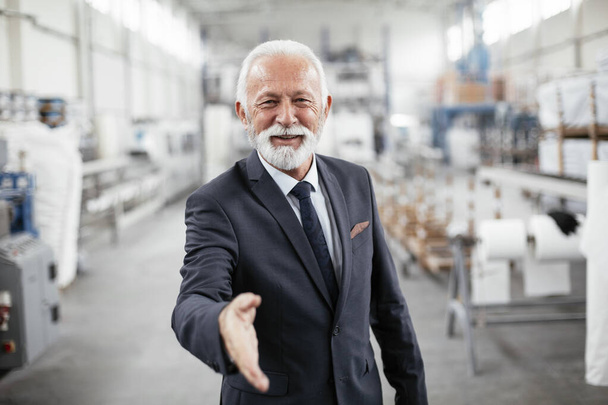 Portret przystojnego starszego biznesmena. Mężczyzna uścisk dłoni w fabryce. - Zdjęcie, obraz